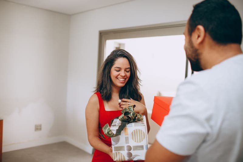 A couple exchanging a wrapped gift at home