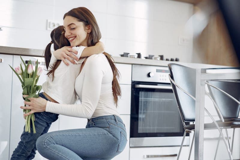 A mother and daughter with a gift in a kitchen