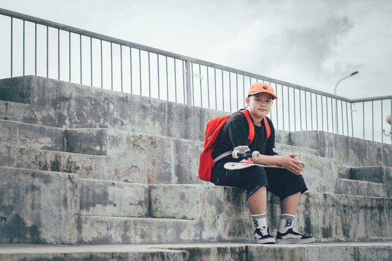 A teenage boy with a backpack and skateboard