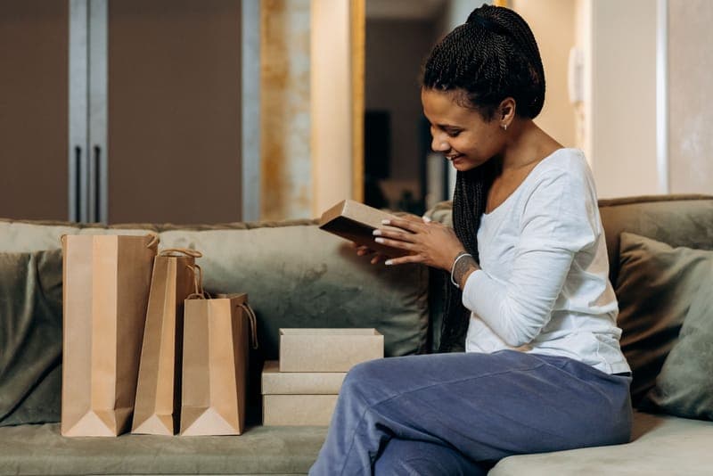 A woman smiling as she opens a gift box