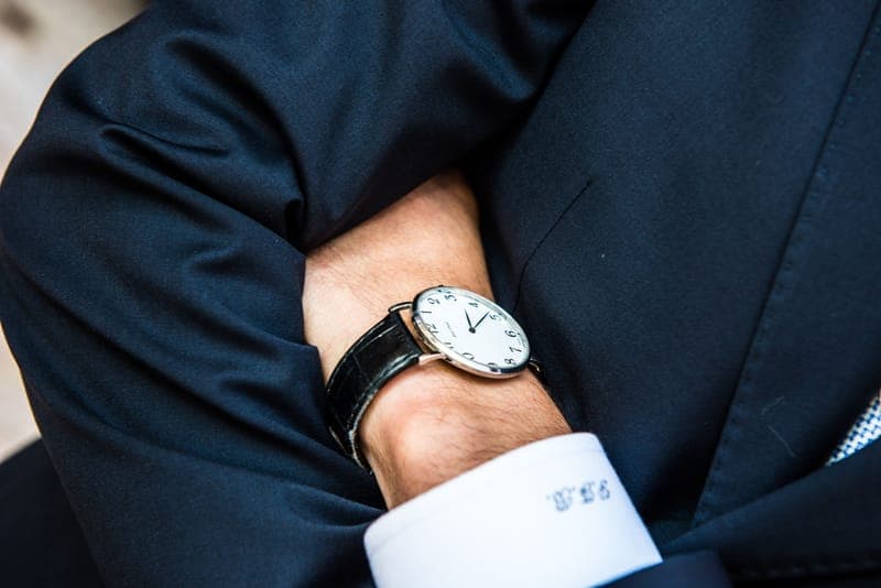 A slim dress watch on a leather strap worn with a suit cuff